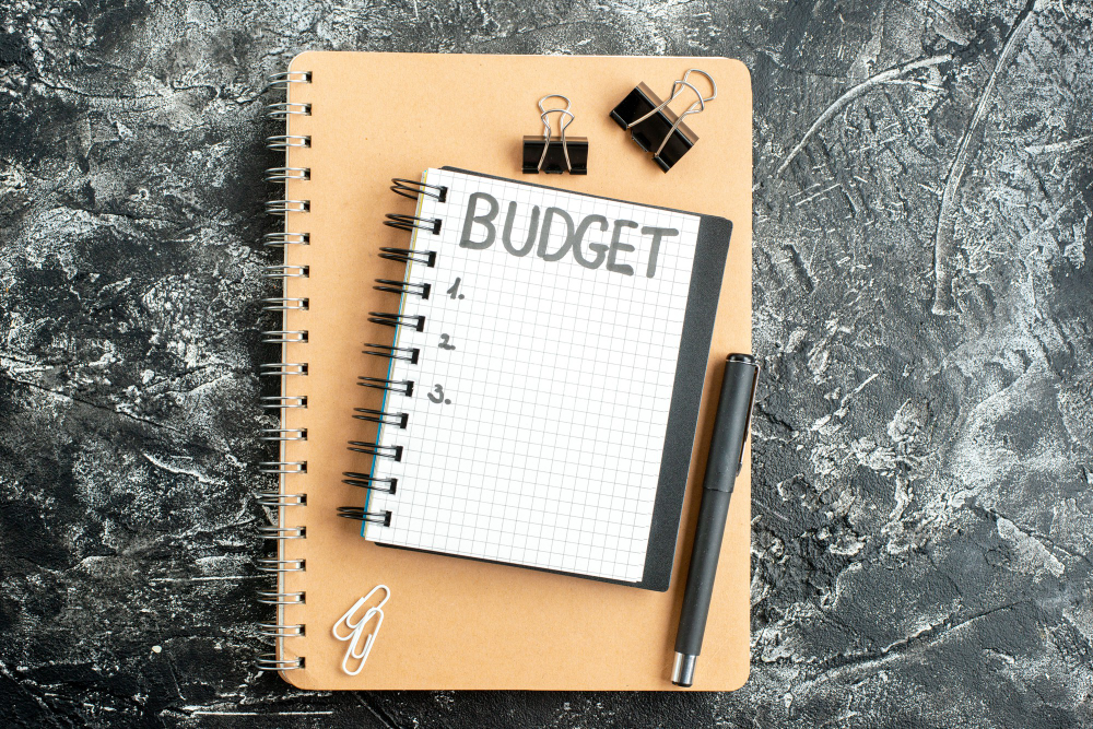 A notepad with the word "budget" written on it on a desk