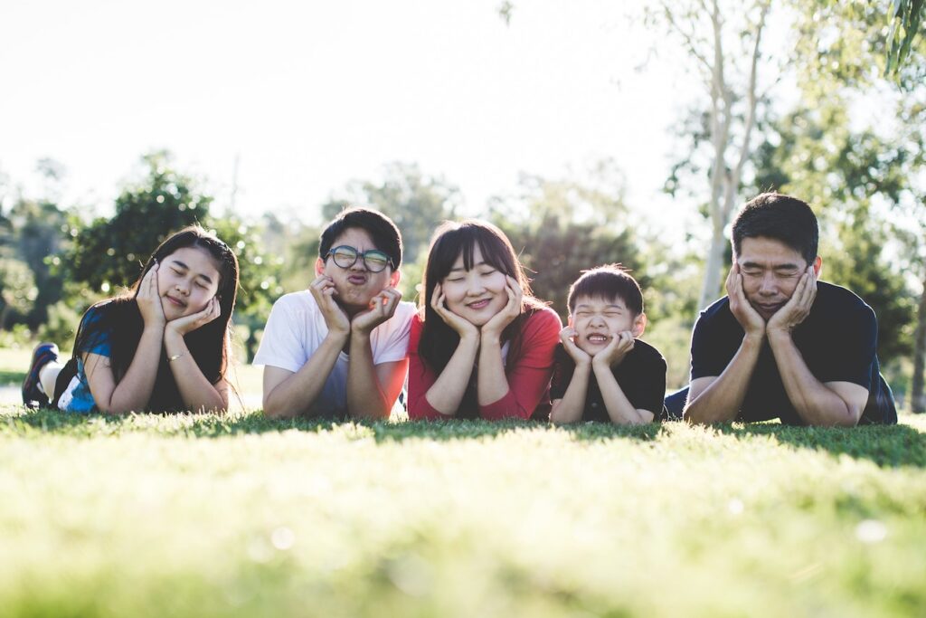 Cute family of five lying on the grass in an open field