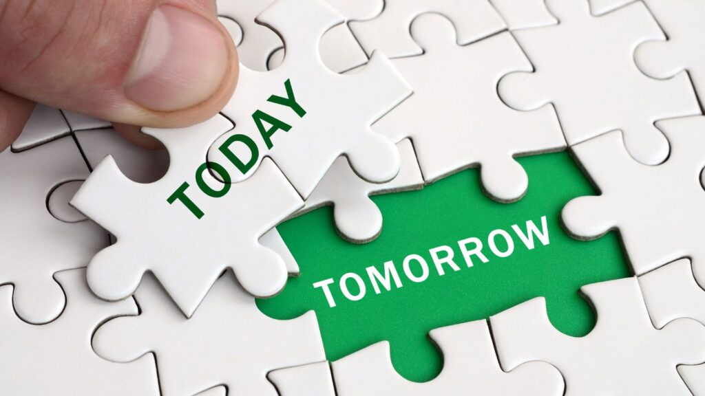 Human hand filling in the last missing puzzle piece -with the words "today" and "tomorrow" written on the piece