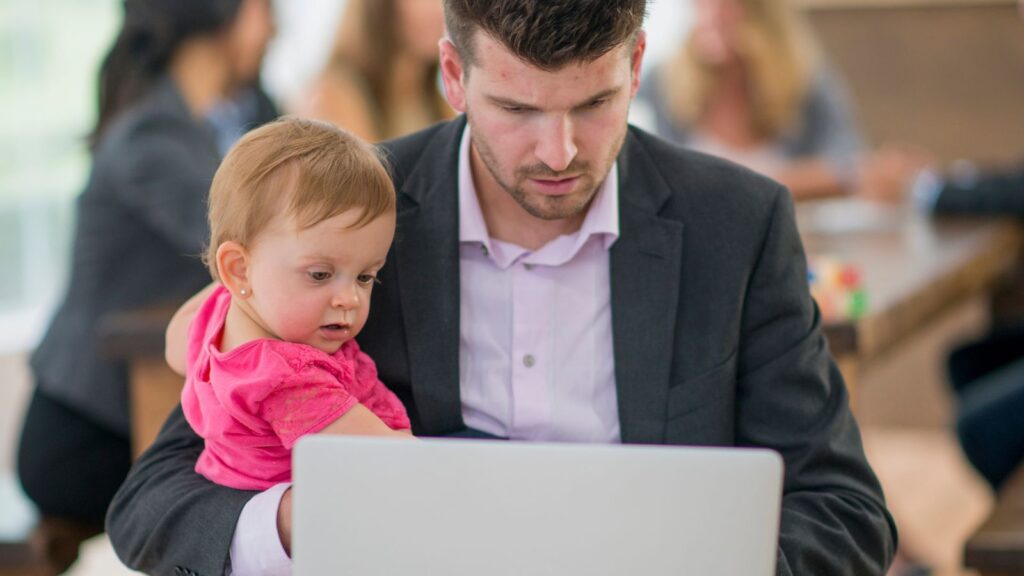 Dad working on his laptop while holding his daughter