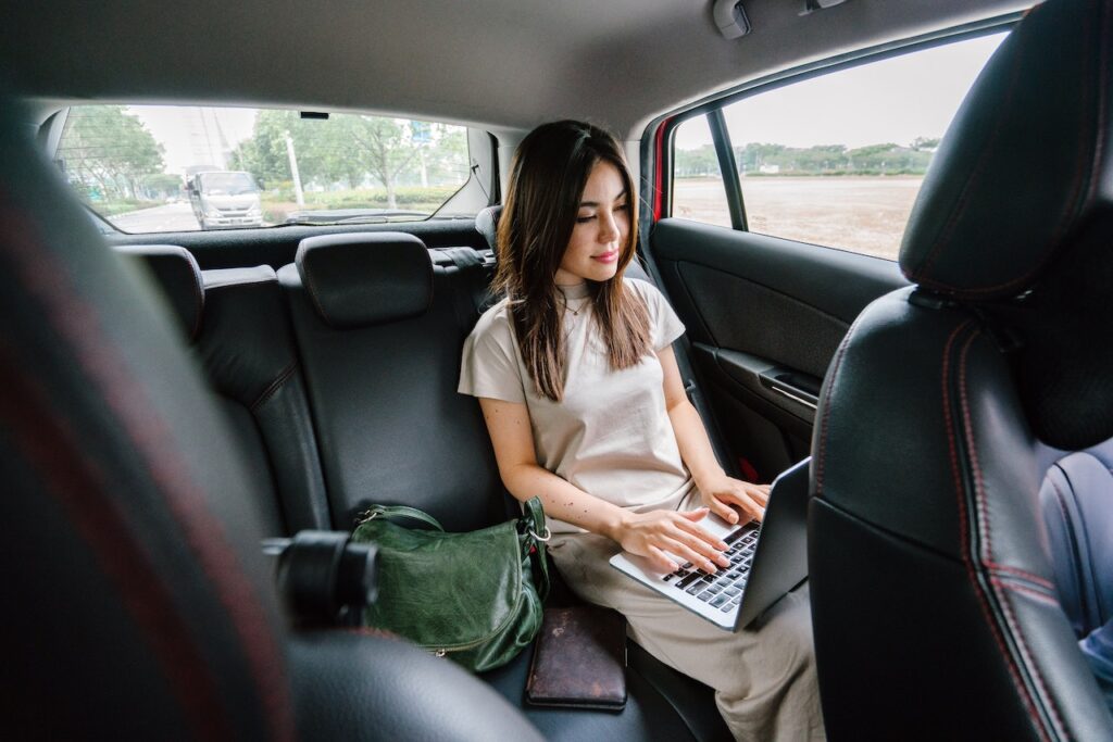 Business Woman on a Business Trip Using Laptop Computer Inside a Vehicle