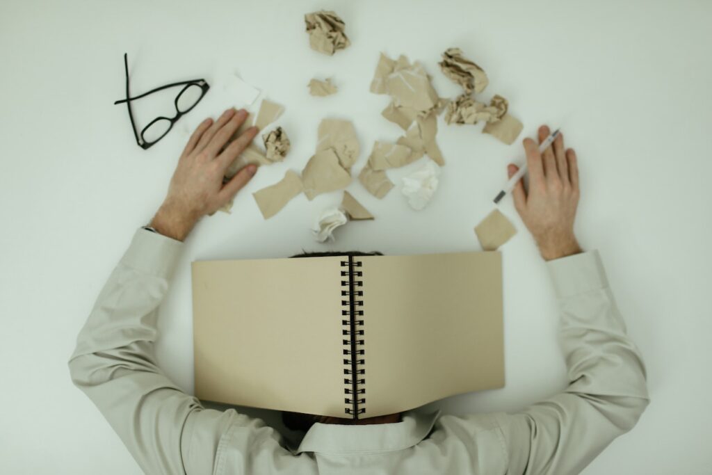 An illustration of a man resting his head on a desk experiencing burnout