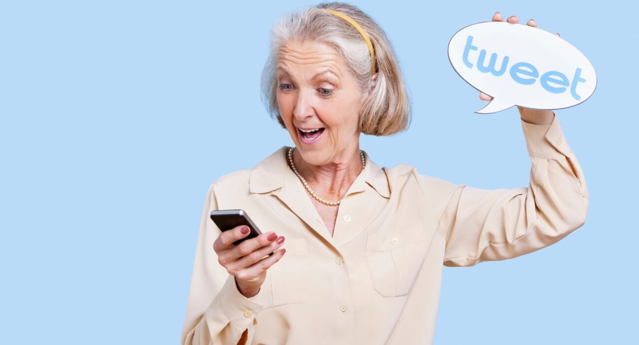 An elderly businesswoman using twitter for her business and holding a tweet sign