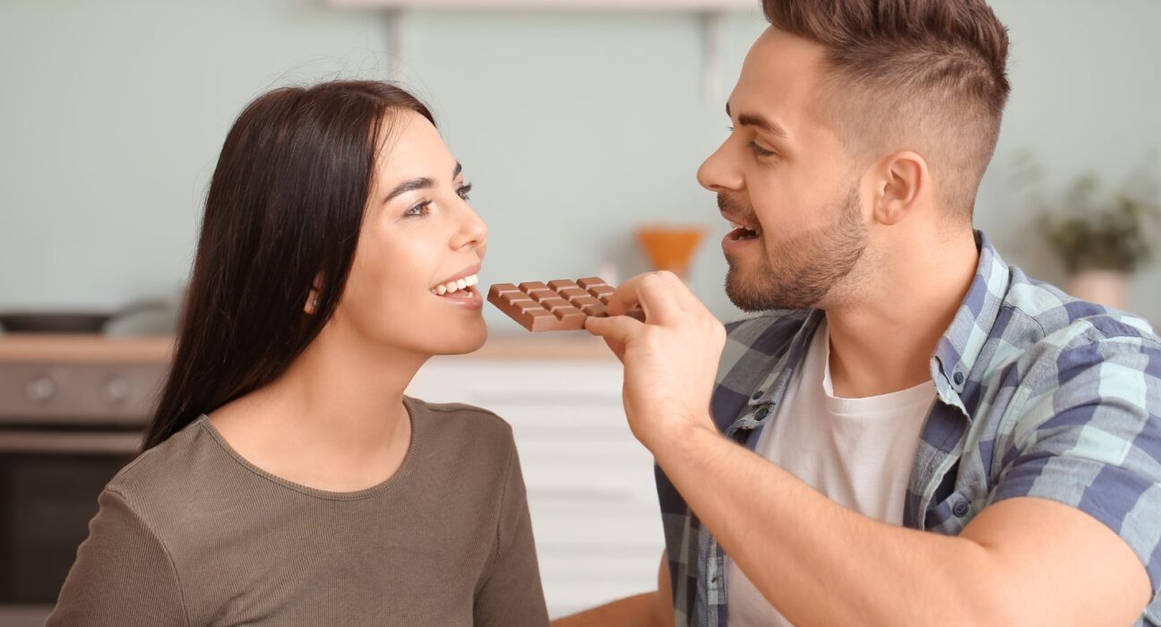 A man feeding his wife chocolate bars